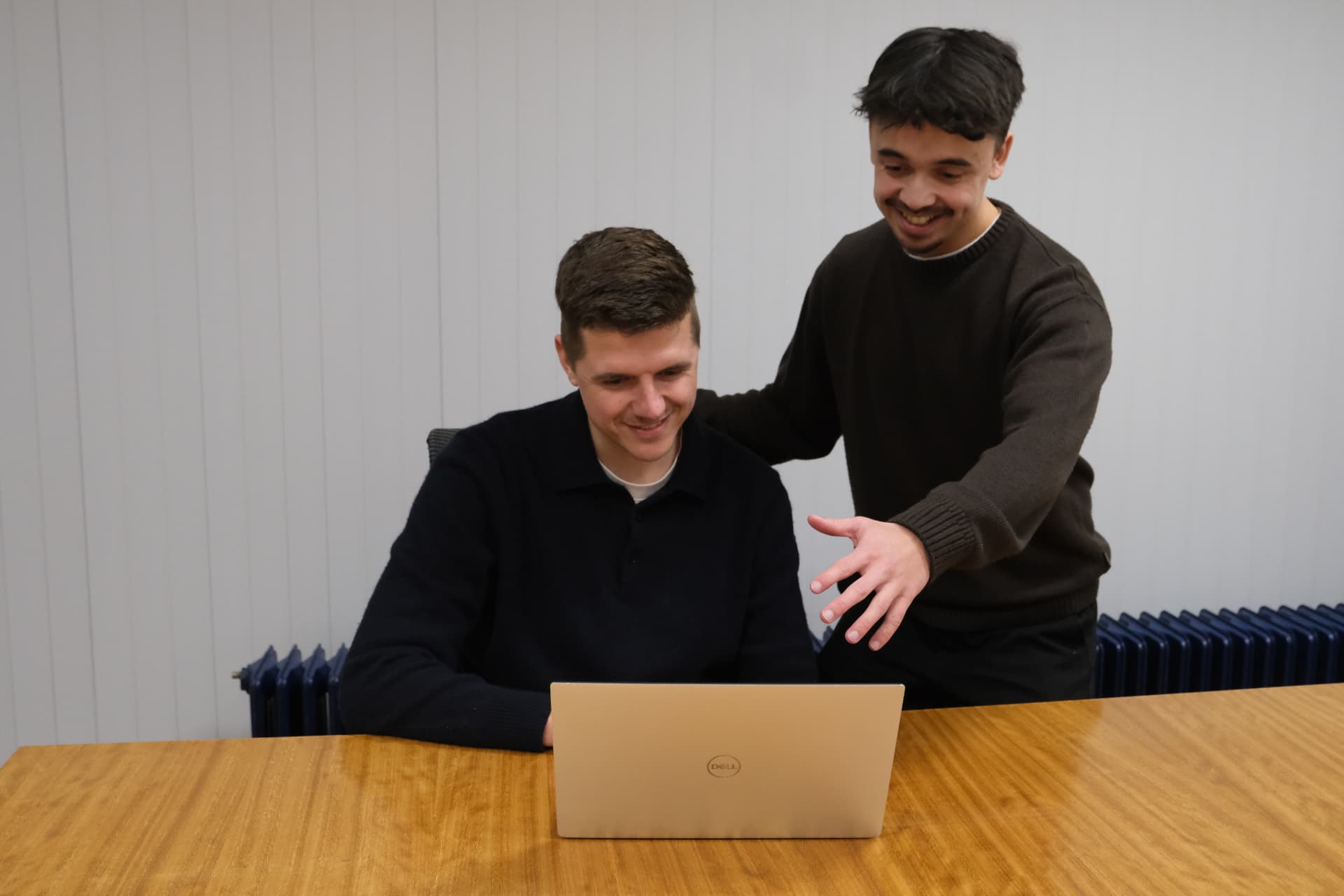 Bart en Didiet van druc lachen samen aan tafel achter een laptop tijdens het bespreken van een website